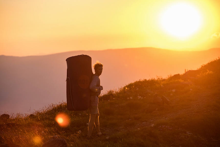 Ein Kletterer und seine Bouldermatte im Sonnenuntergang auf der Koralpe