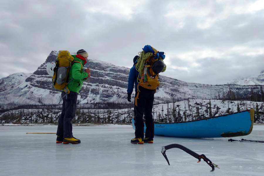 Eiskletterer mit Kanu auf zugefrorenem Fluss