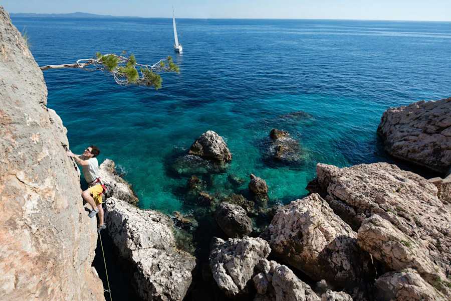 Christoph klettert an der Westseite des freistehenden Turmes (Cliff Bay/Hvar) mit Blick auf das Segelboot „Mandy“