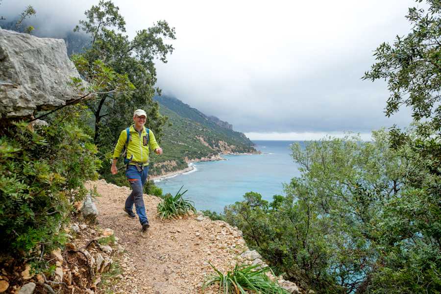 Wandern auf gemütlichen Wegen in üppigem Grün, während die Wellen unterhalb gegen die raue Felsküste Sardiniens klatschen