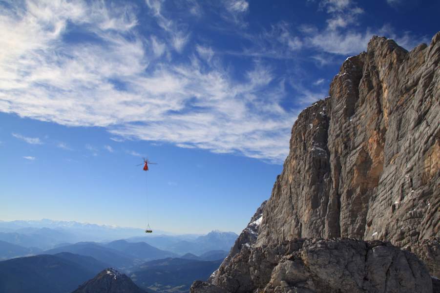 Per Hubschrauber wird das Bauholz zur Baustelle transportiert.