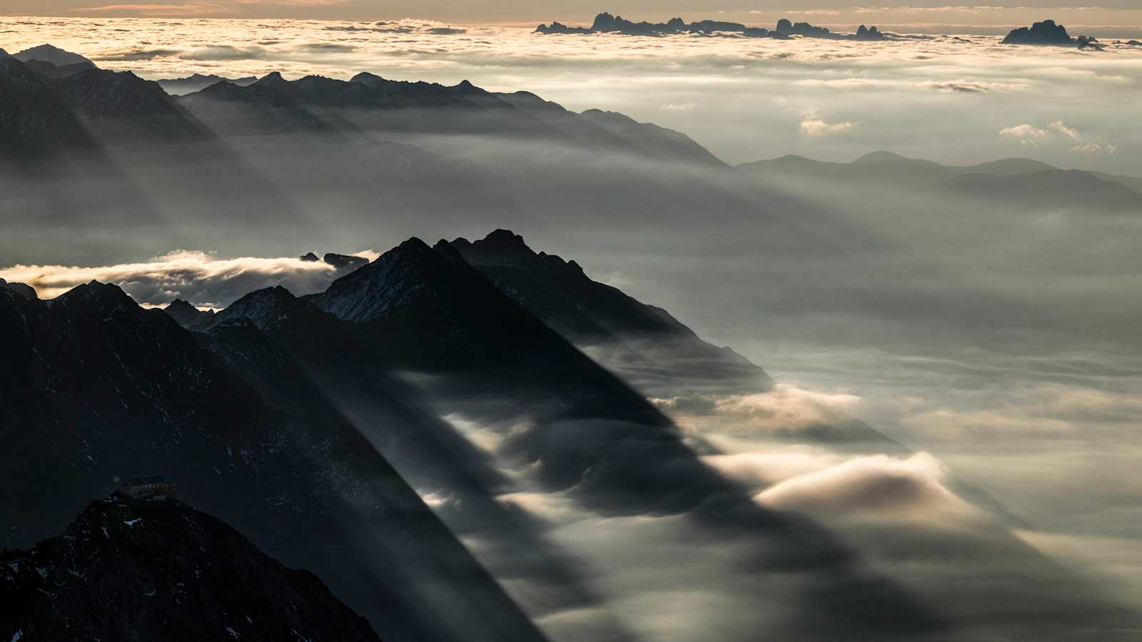 Das Nebelmeer aus Südtirol brandet an die südlichen Ausläufer der Stubaier Alpen. Im Vordergrund steht exponiert das Becherhaus, ganz hinten ragen die Spitzen der Dolomiten aus dem Nebel