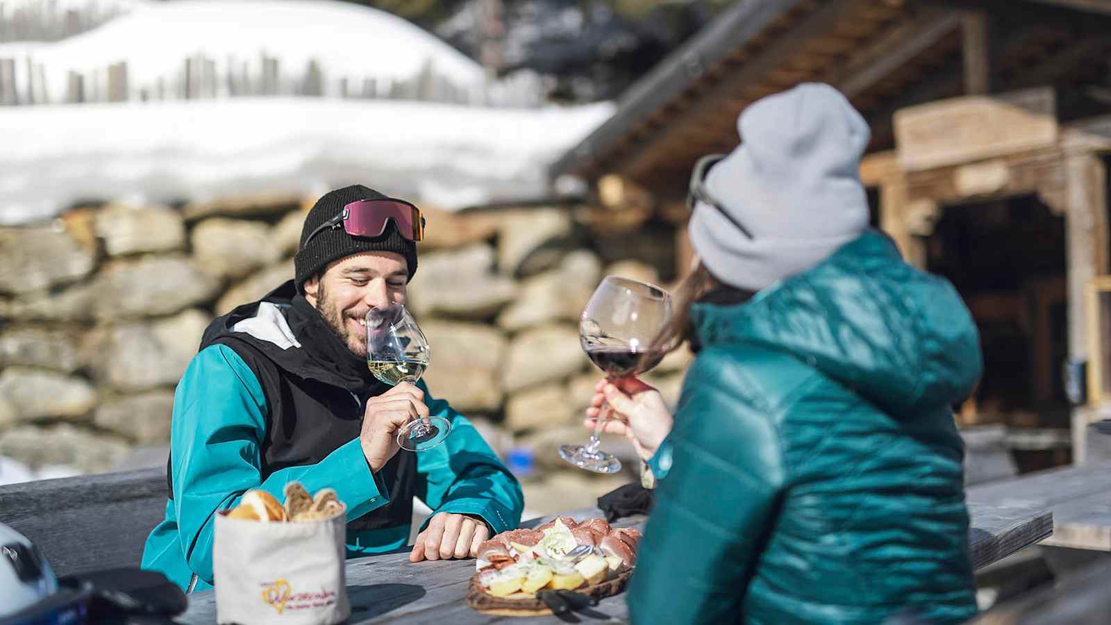 Frau und Mann beim Einkehren auf einer urigen Hütte in Ratschings mit Jause und Wein.