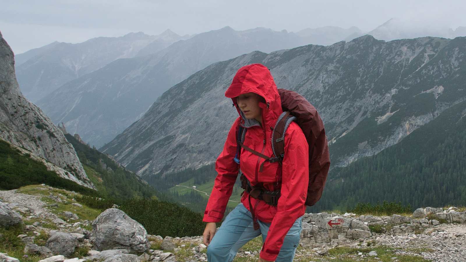 Bergsteiger mit roter Jacke bei schlechtem Wetter