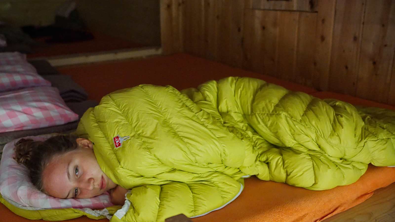 Mädchen in Schlafsack auf einer Berghütte