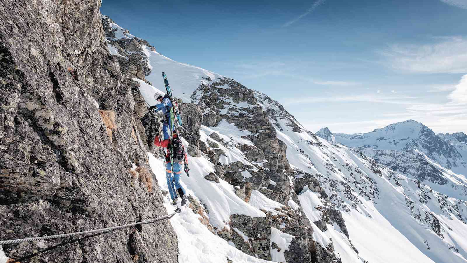 Ein Stahlseil in Fels und Schnee: Mit Skiern am Rücken und Skischuhen an den Füßen geht es am Arlberger Winterklettersteig am Rendl in Richtung Rossfallscharte.