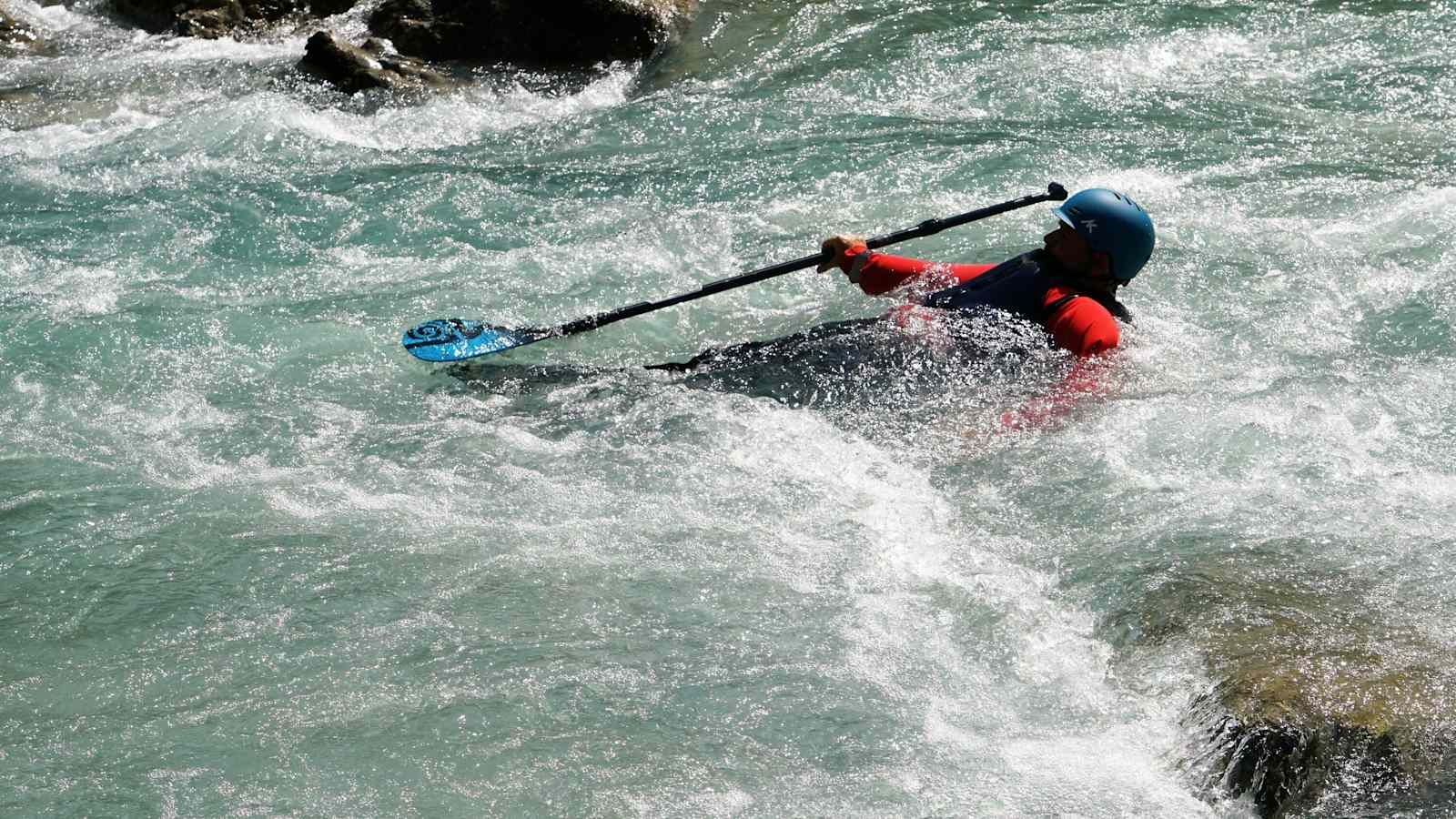 Mann im Wildwasser mit einer Weste mit Prallschutz