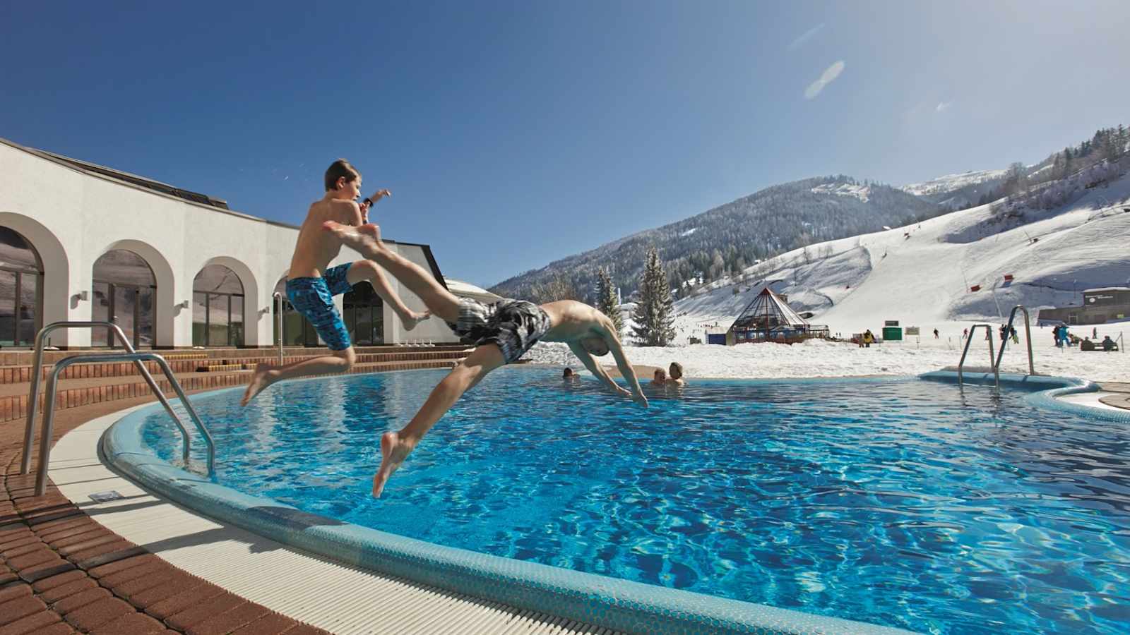 Therme Römerbad mit Außenbecken und direktem Blick auf die Skipiste. 