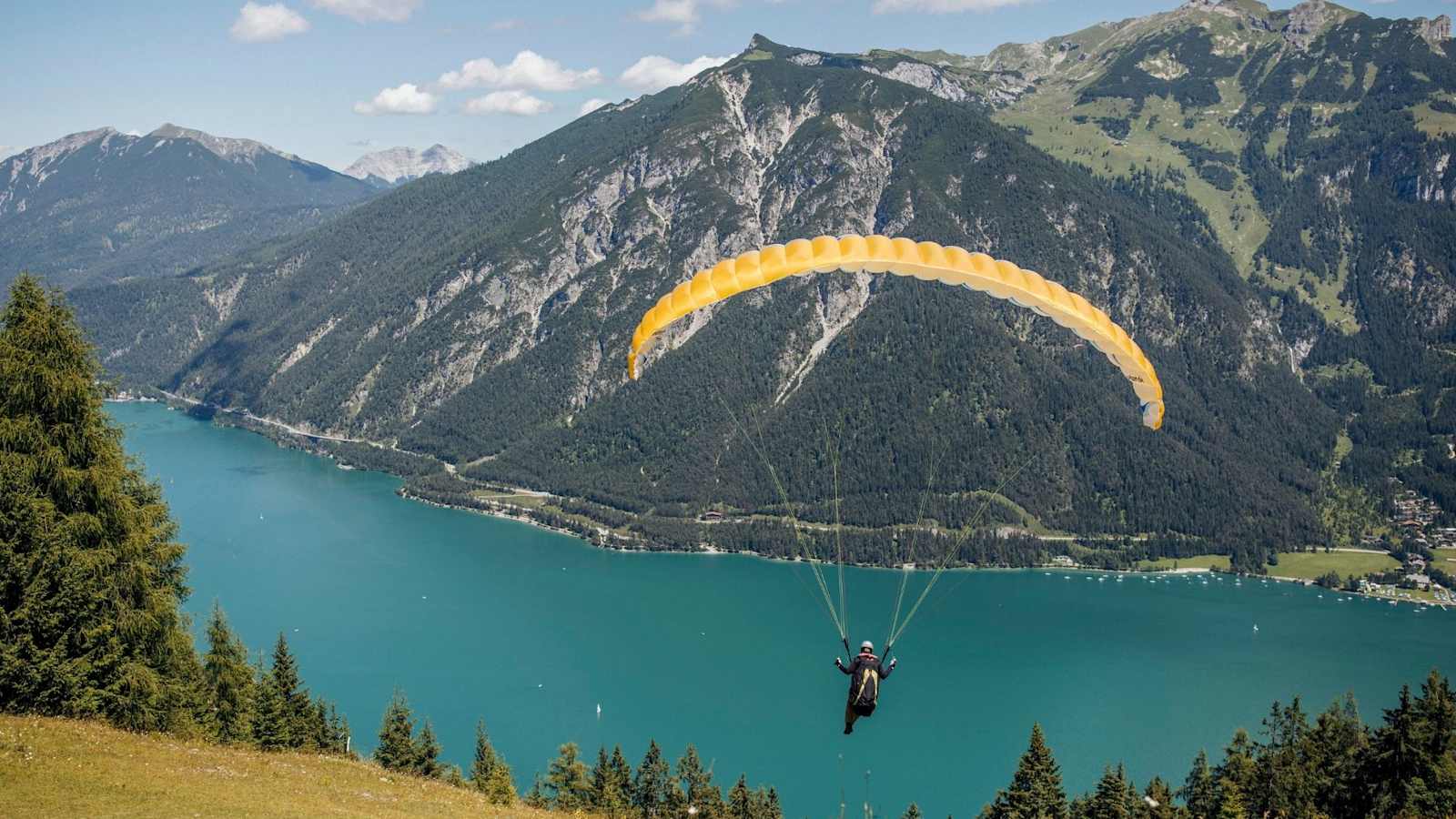 Ein Paragleiter startet über den Achensee hinaus