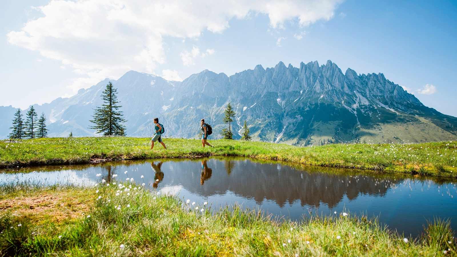 Bergsteiger wandern entlang eines kleines Bergsees.