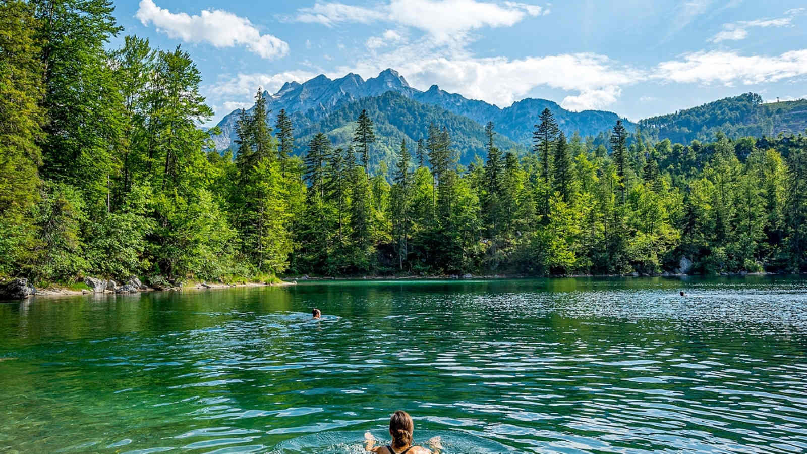 Eine Frau schwimmt im Bergsee.