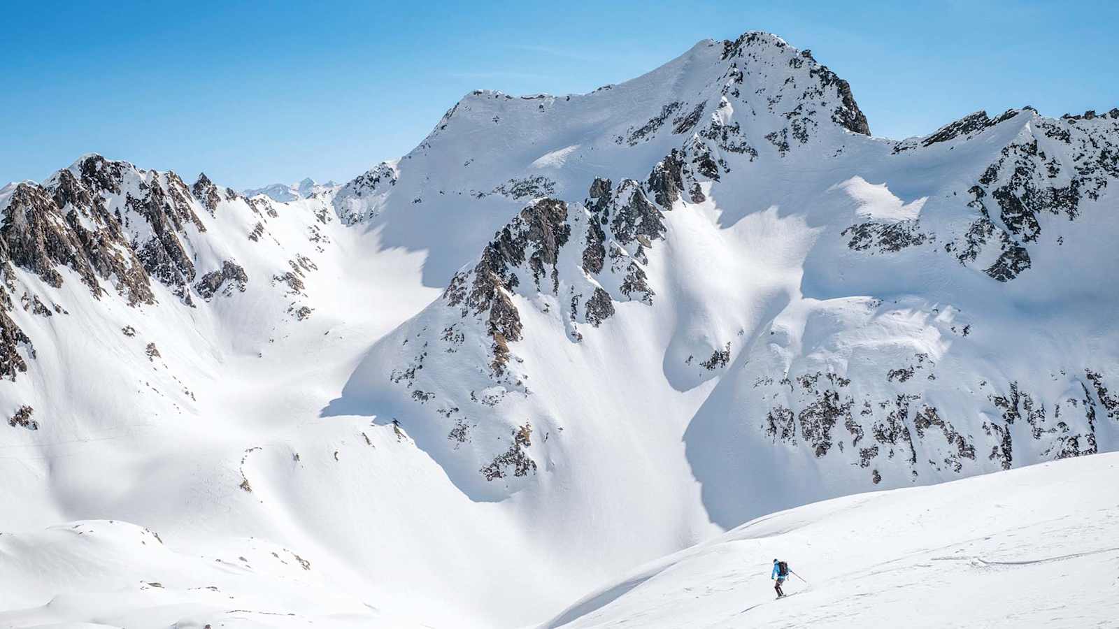 Ein Skifahrer bei der Abfahrt, dahinter der Cristallinagipfel.