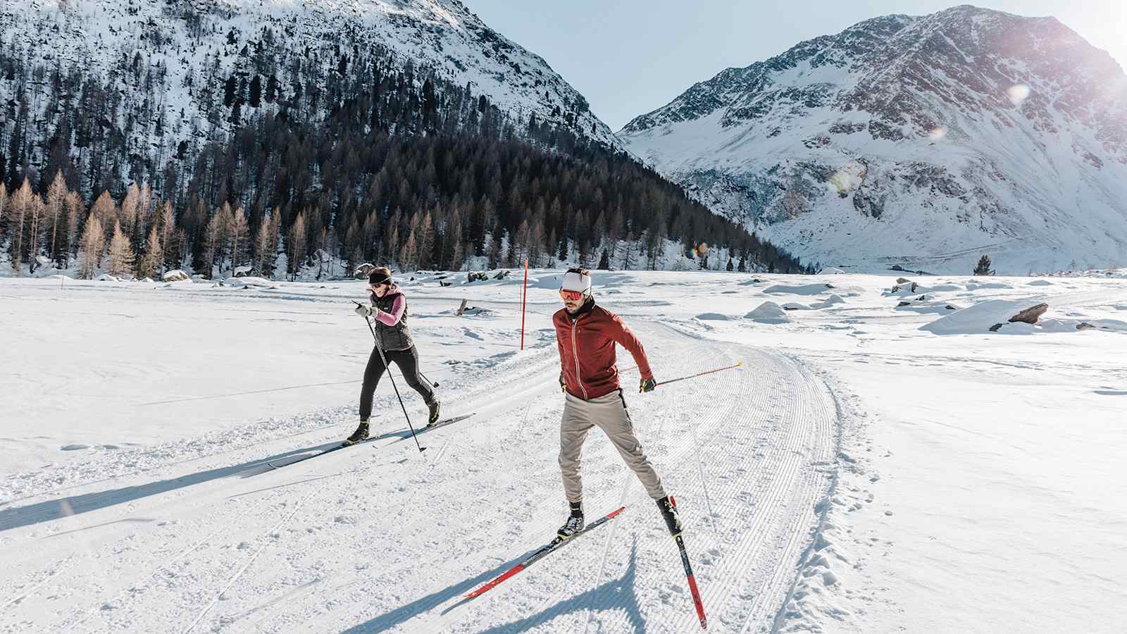 Eine Frau und ein Mann auf ihren Langlaufskiern in der verschneiten Natur Merans.