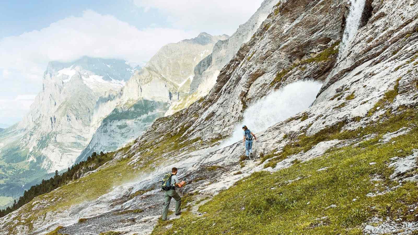 Bergsteiger vor einem Wasserfall.