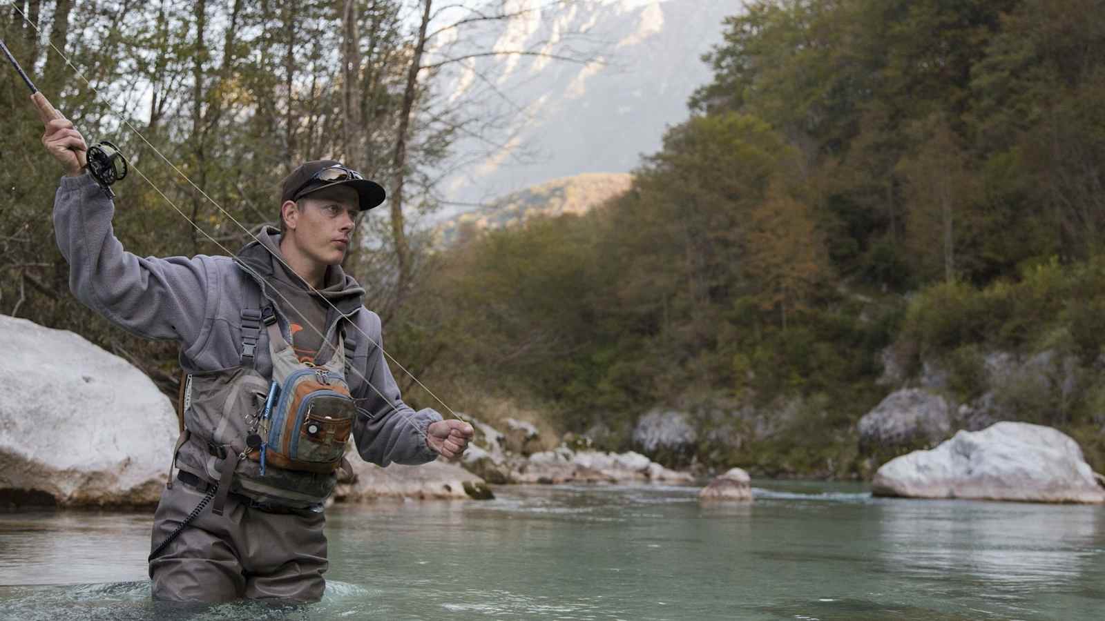 Der Angler im türkisen Wasser wirft die Rute aus.