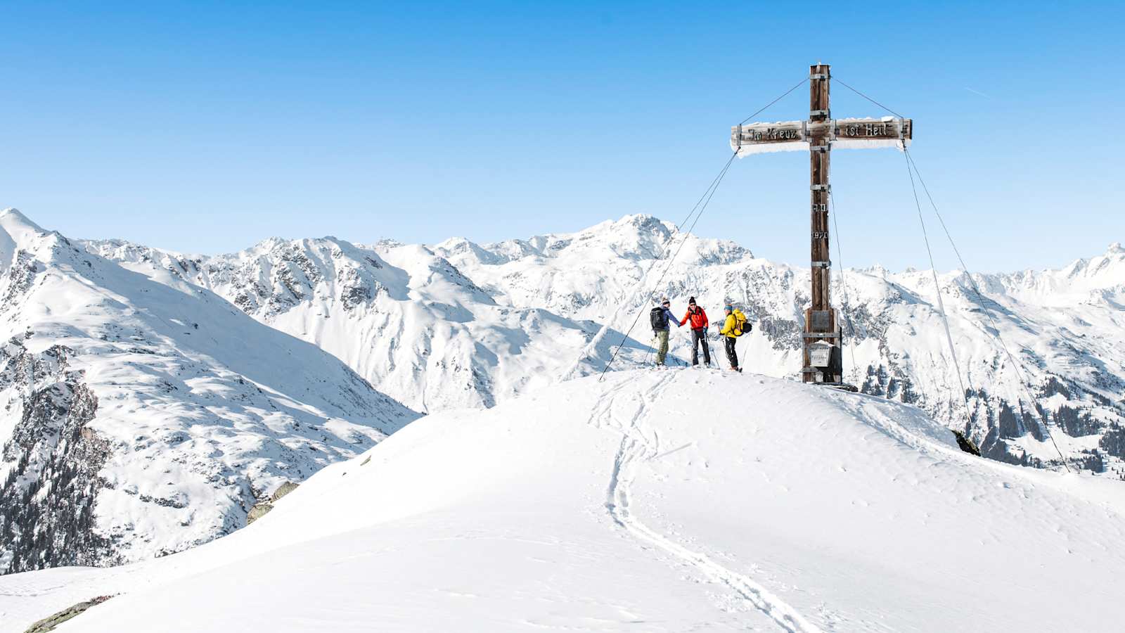 Drei Tourengeher beim Gipfelkreuz