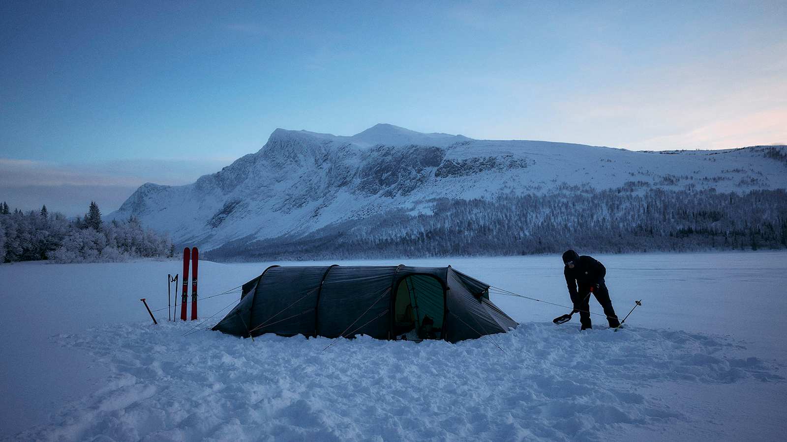 Wintercamping in verschneiter Berglandschaft, perfekt ausgerüstet mit Haglöfs Outdoor-Bekleidung und -Ausrüstung.