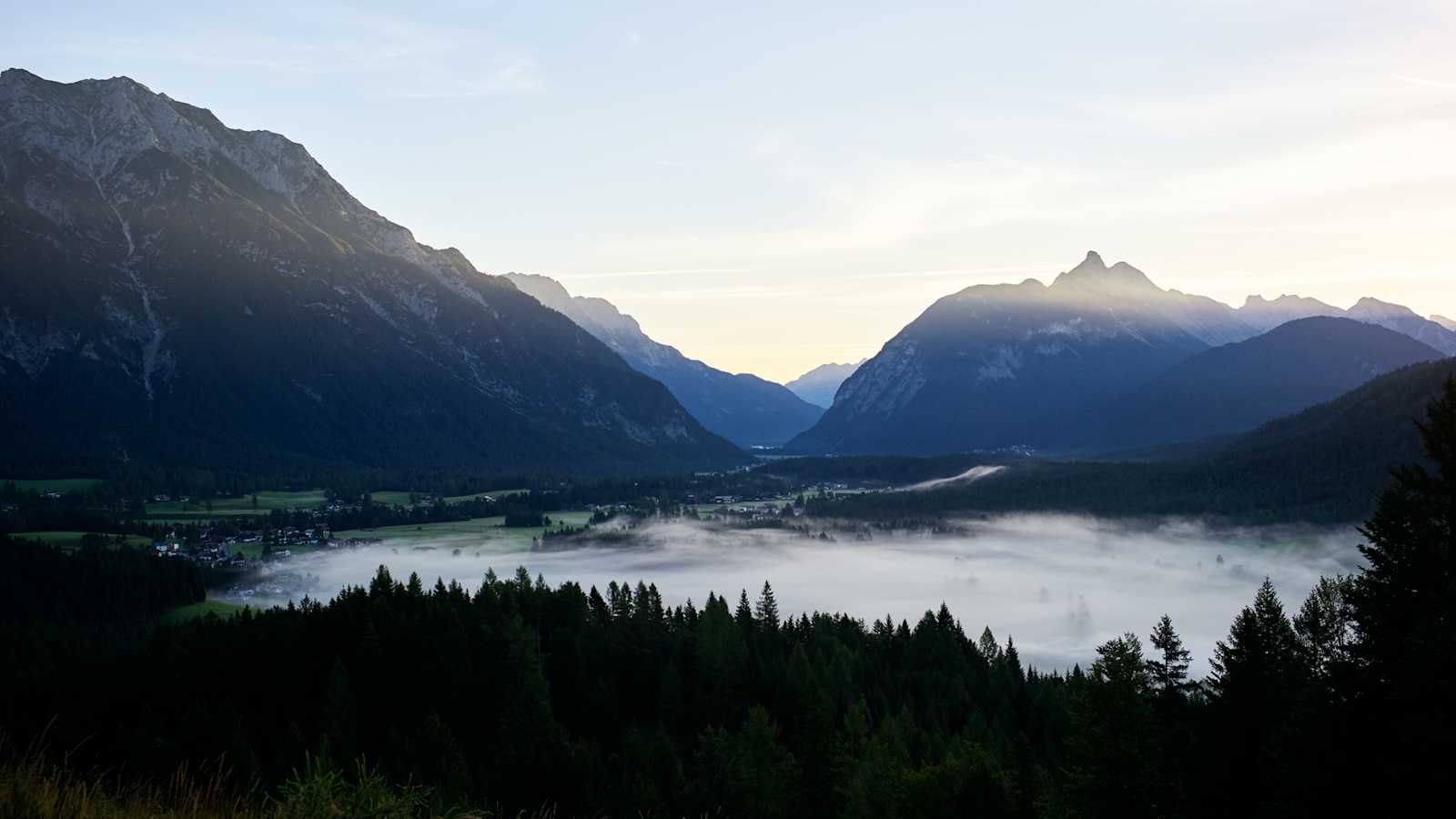 Nebel liegt unter den Bergen.