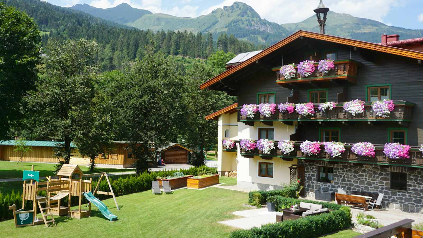 Bio Bauernhof Kendlgut in Badhofgastein umringt von Bäumen und Bergen im Hintergrund