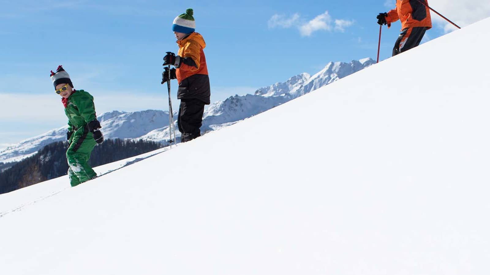 Kinder fahren mit den Skiern den Hang hinunter.