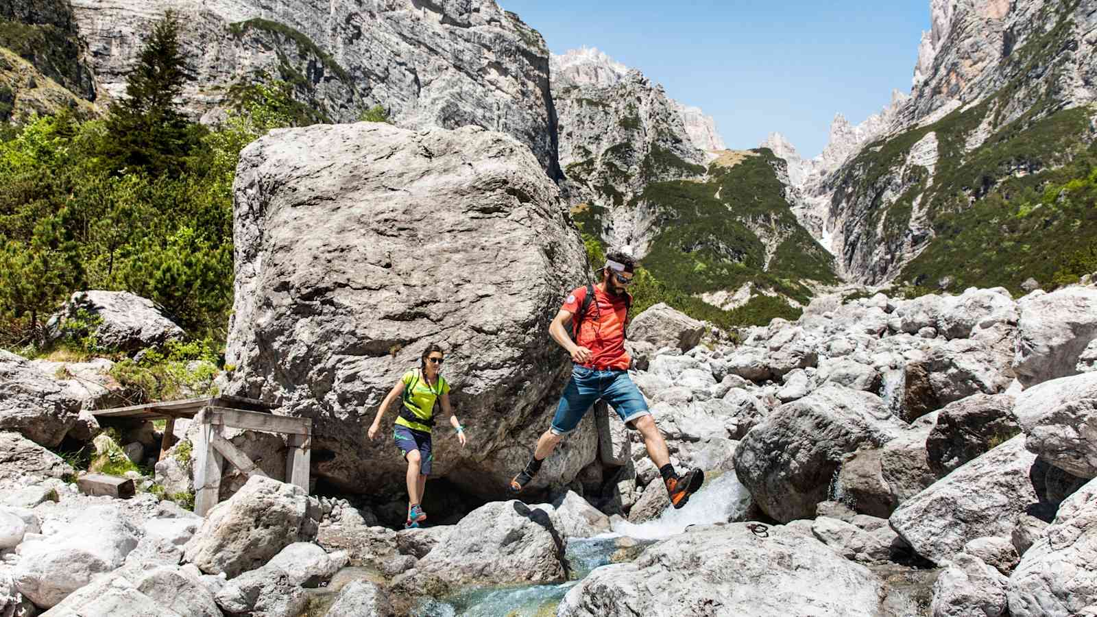 Zwei Bergwanderer beim Überqueren eines Flusses.