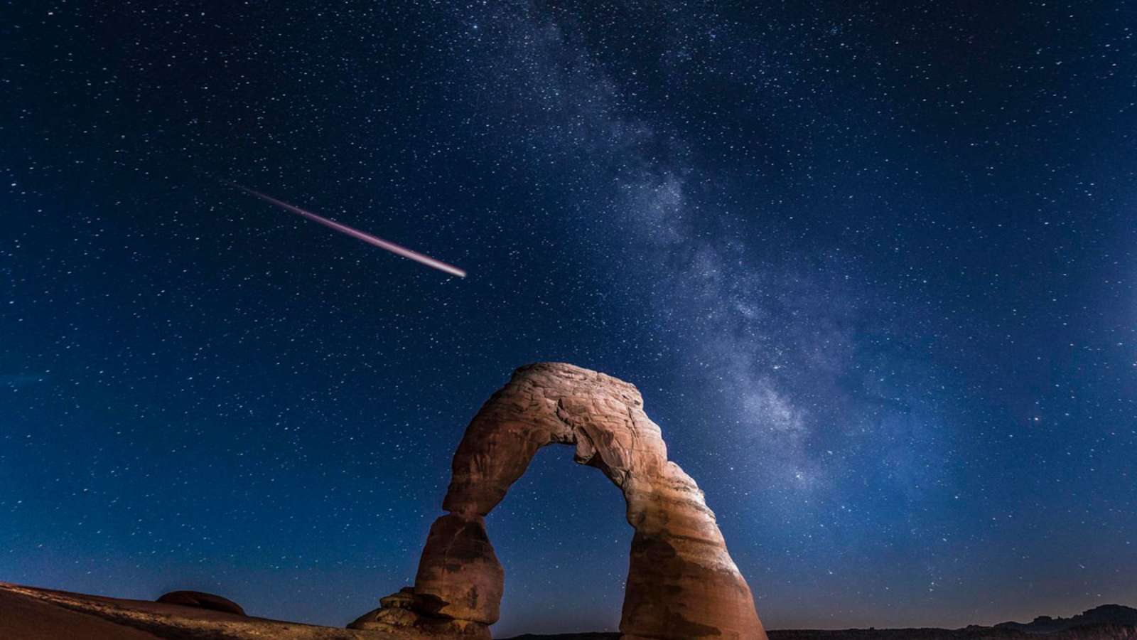 Der Felsbogen Delicate Arch mit der Milchstraße und einer Sternschnuppe im Hintergrund, Arches Nationalpark in Utha, Nordamerika