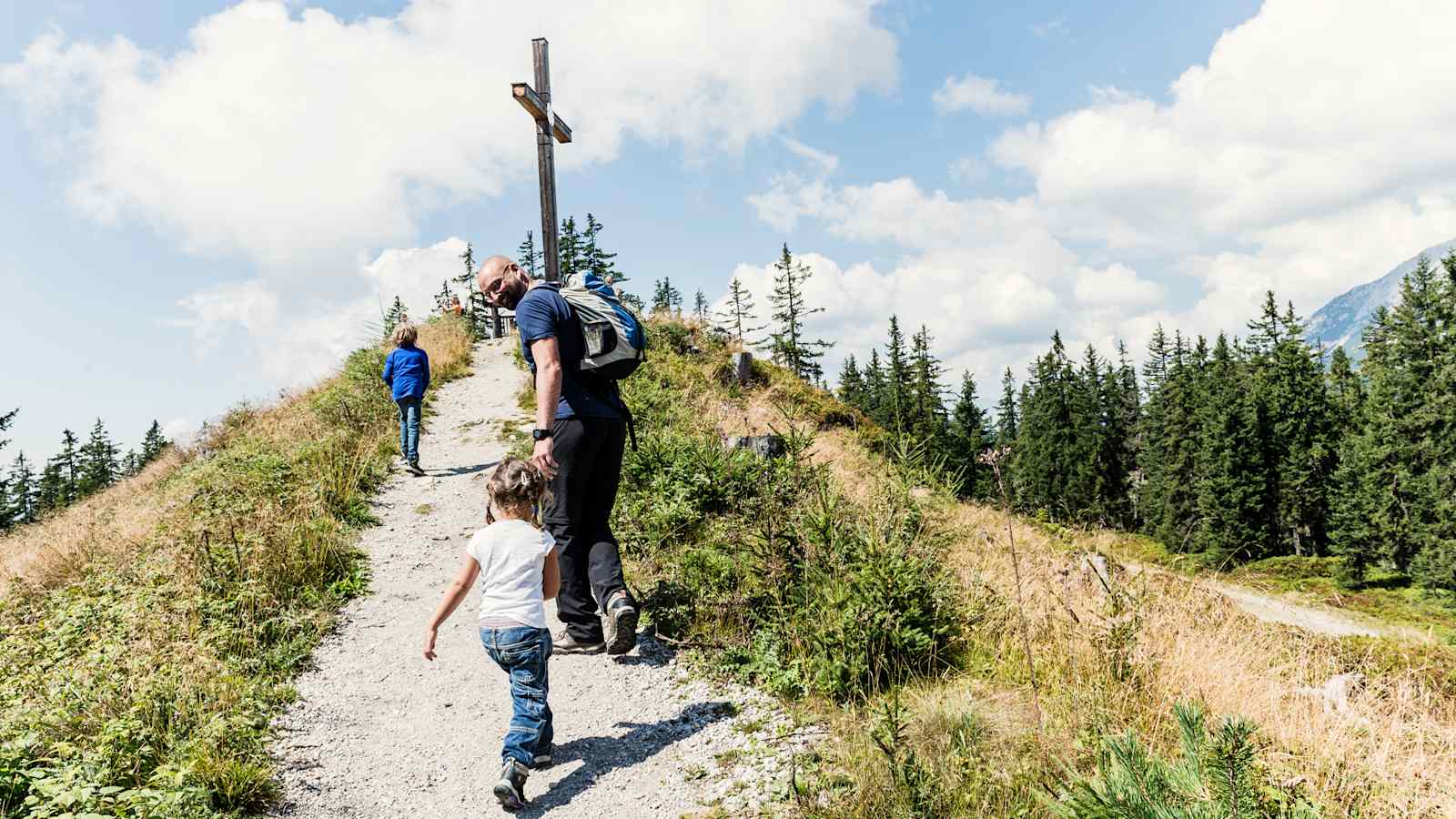 Die drei Wanderer haben das Gipfelkreuz erreicht. 