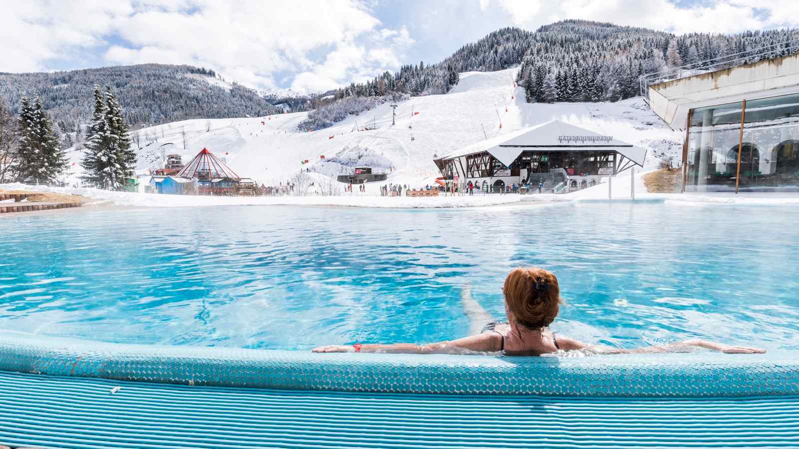 Vom Außenpool des Römerbades kann man den Skifahrern auf der Piste zusehen.