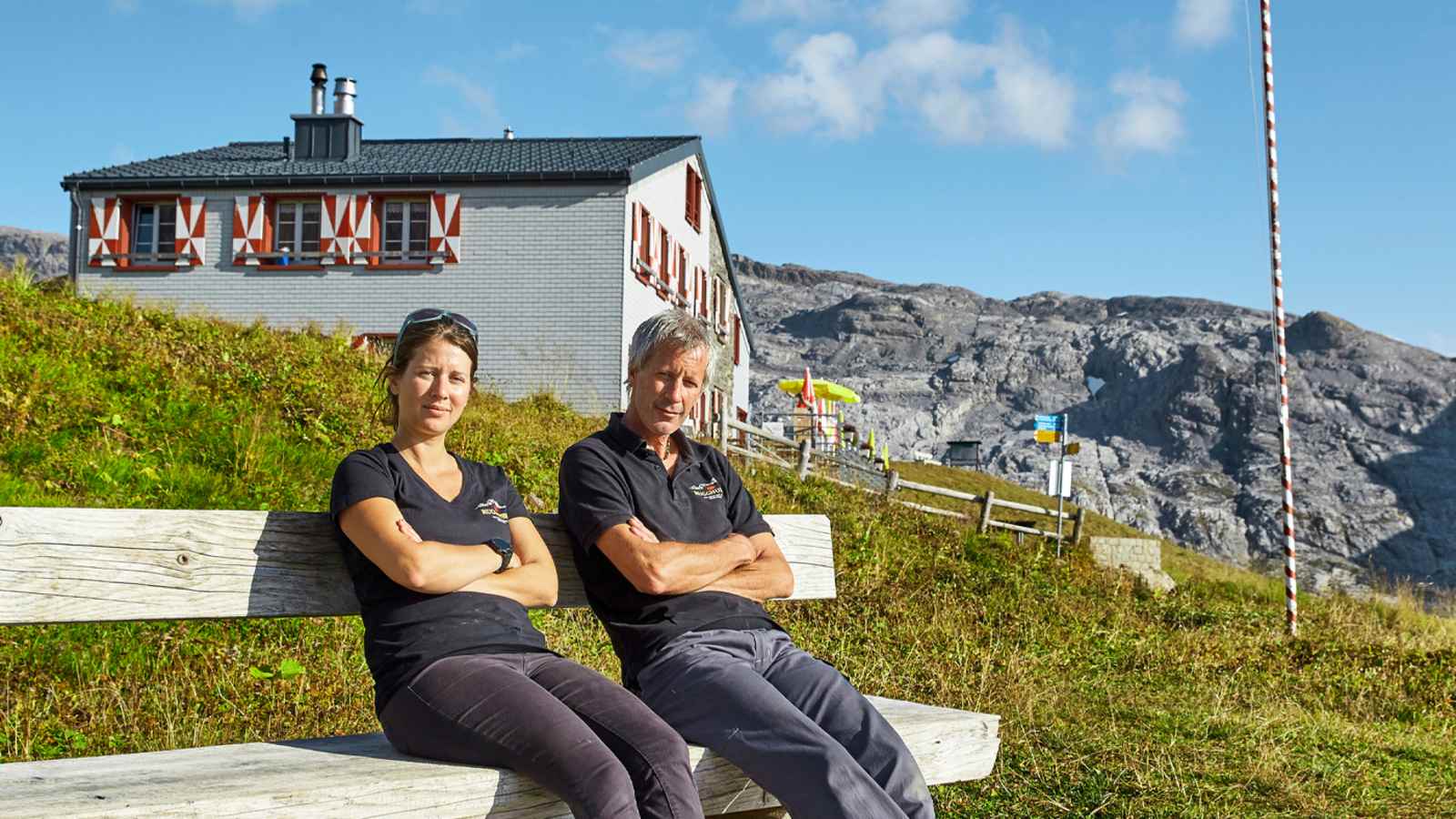 Die Hüttenbetreiber sitzen auf einer Bank vor der Hütte.