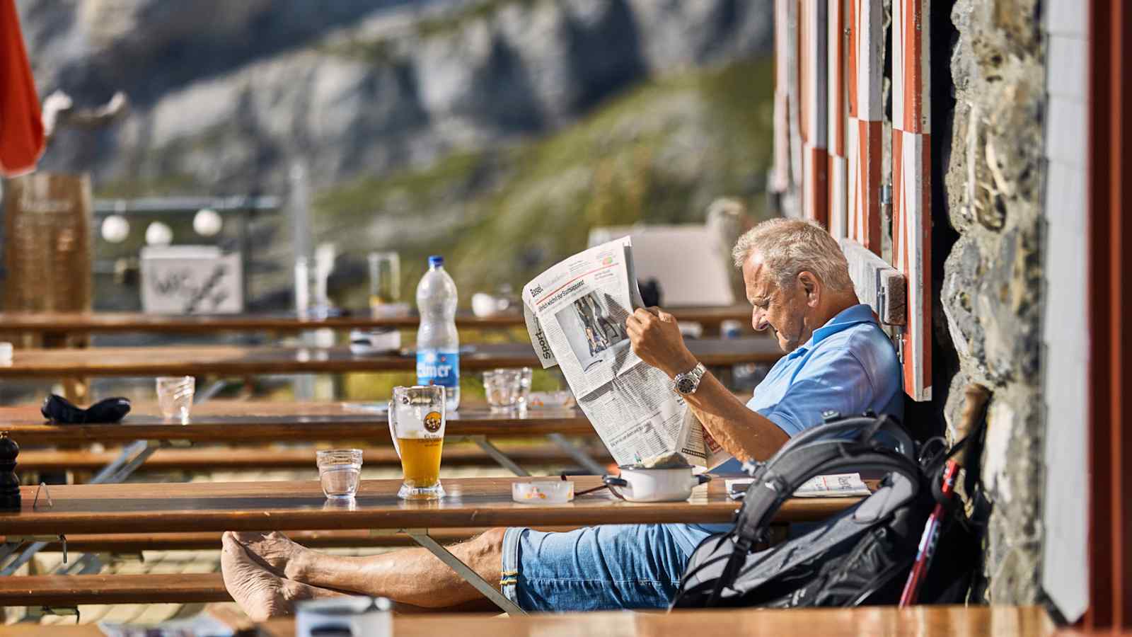 Ei Mann ließt Zeitung und genehmigt sich ein Bier.