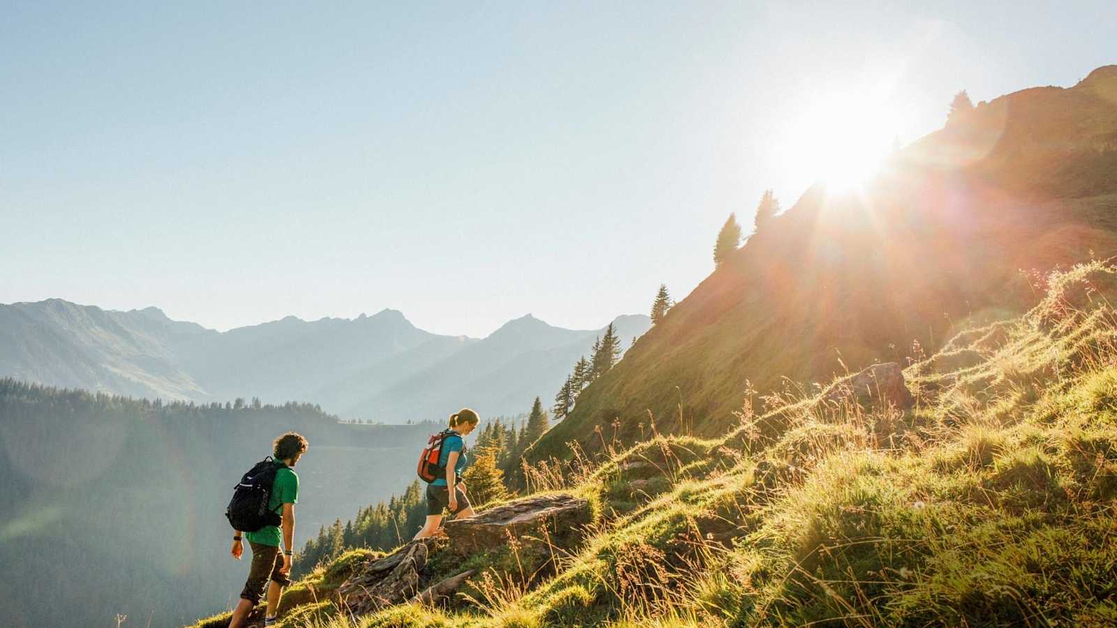 Das Sonnenlicht streift die Grasberge des Glemmtals