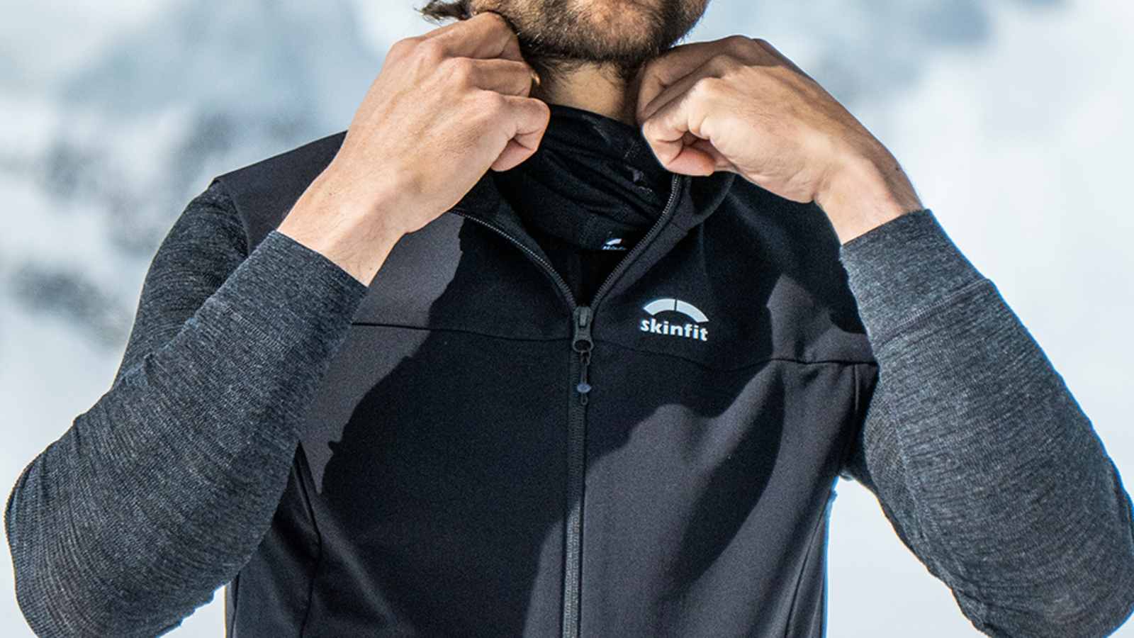 Ein Mann auf dem schneebedeckten Berg bei einer Hochtour in seinem skinfit Outfit und Brille