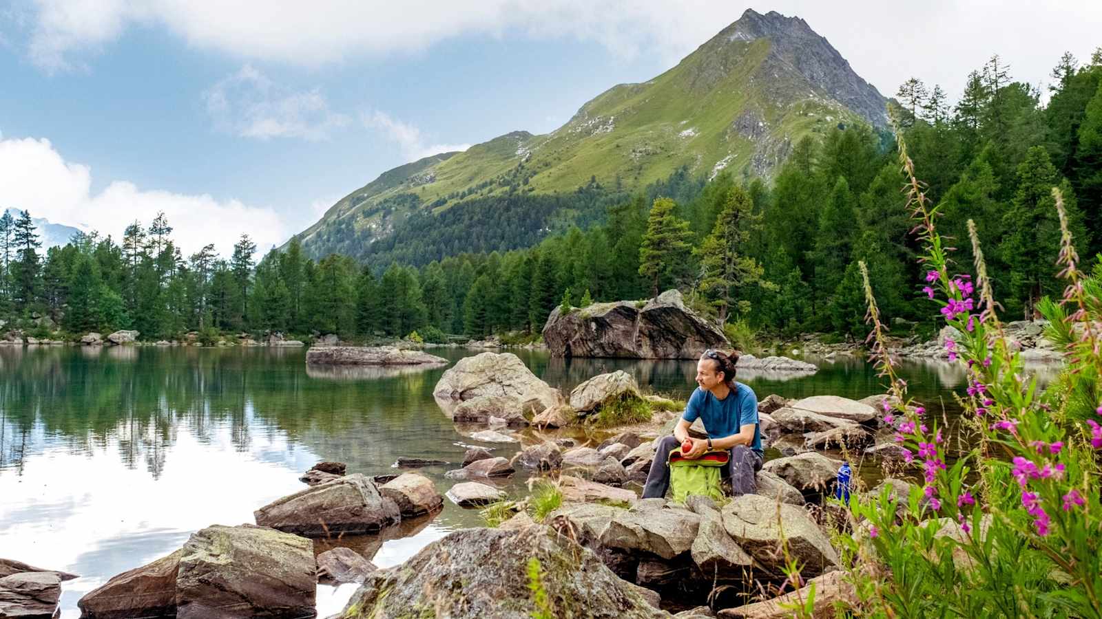 Ein Wanderer ruht sich am Wasser aus.