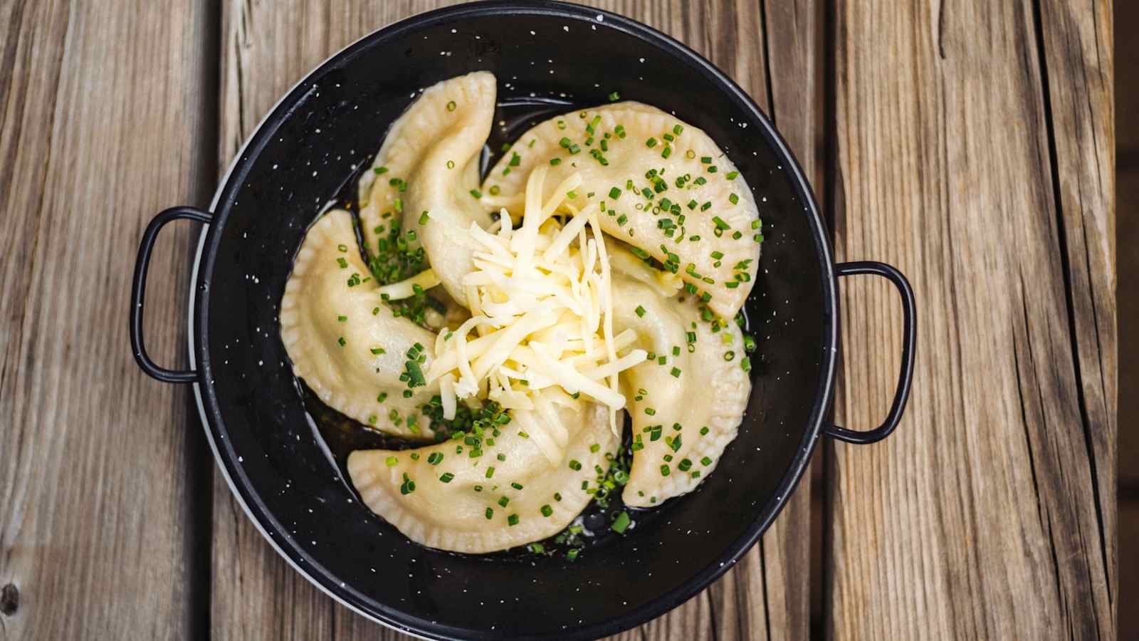 Frische Schlutzkrapfen mit geriebenem Käse in einer Rein serviert.