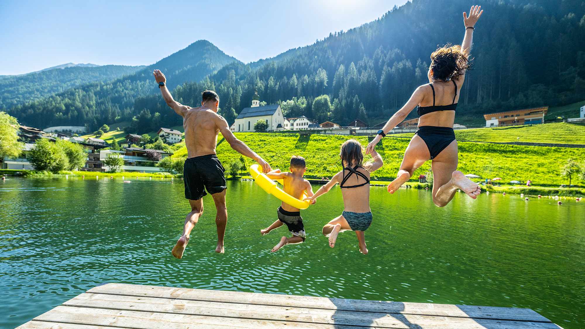 Eine Familie springt in See in den Badesee.