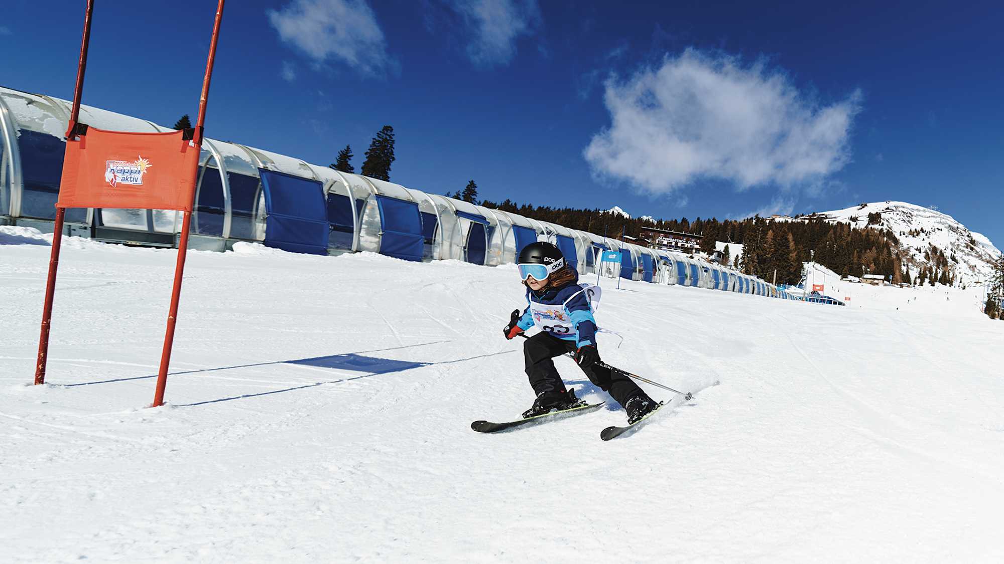 Ein Kind fährt den Übungshang im Skigebiet Kappl hinunter und fährt dabei an einem Tor vorbei.