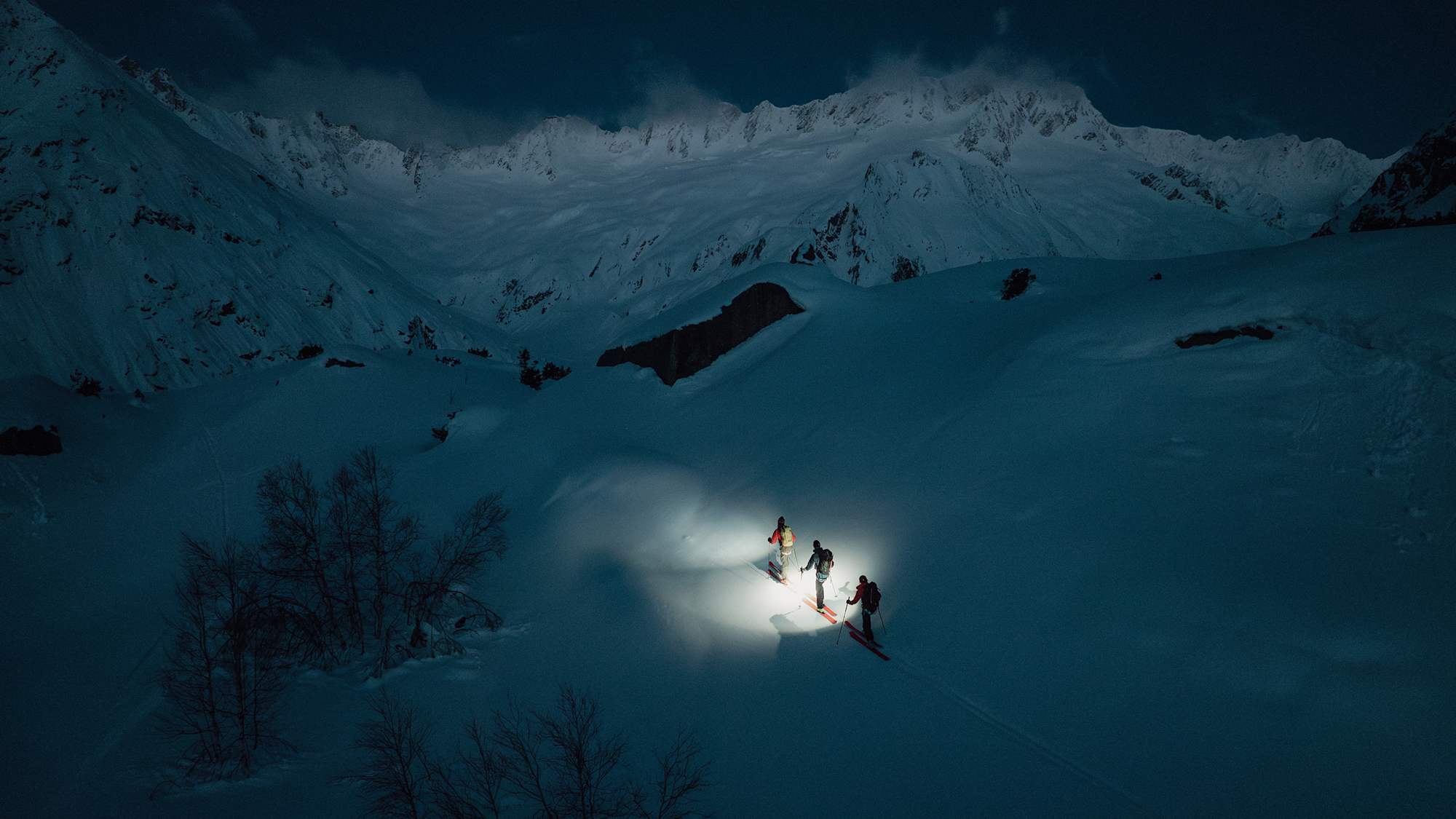 Drei Skitourengeher gehen in der Dunkelheit eine Tour in den Schweizer Alpen.