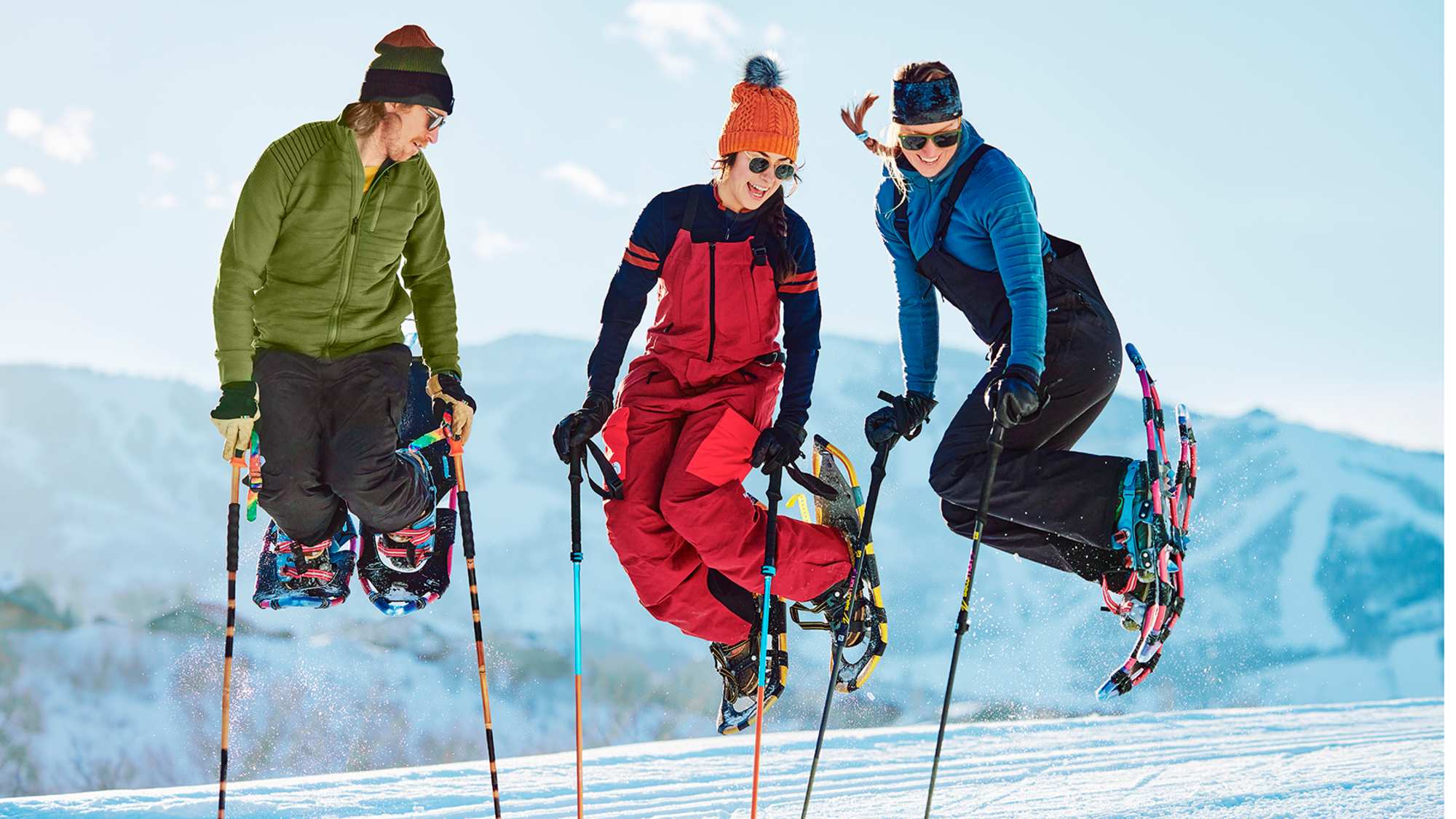 Drei Freunde haben Spaß im Schnee mit Schneeschuhen in Smartwool-Outfits.