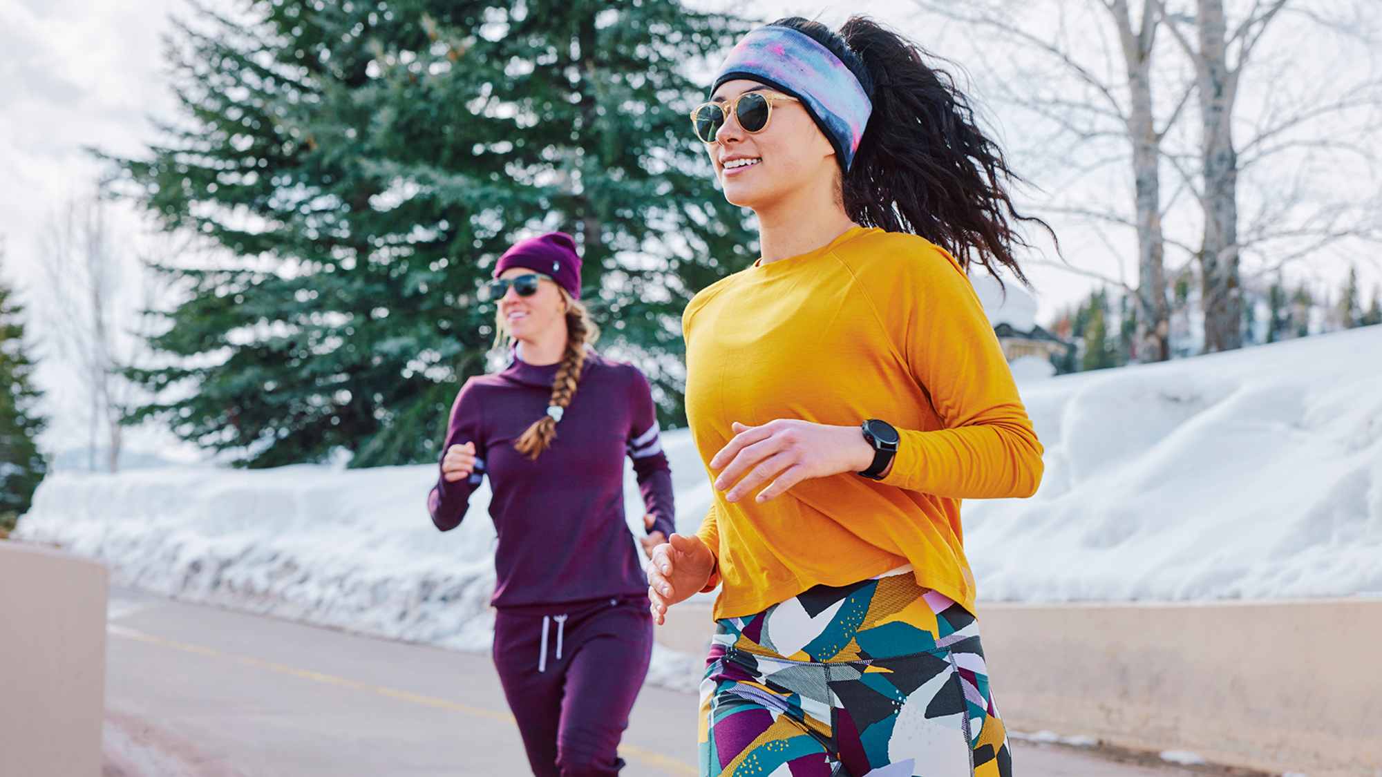 Zwei Frauen laufen in Smartwool Outfits im Winter.