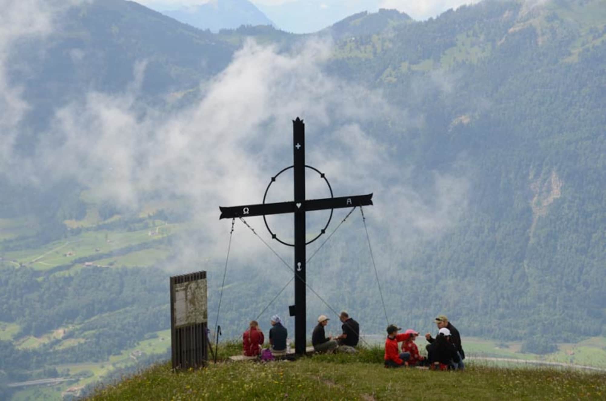 Wanderer geniessen den Gipfel des Gnipen mit dem Gipfelkreuz.