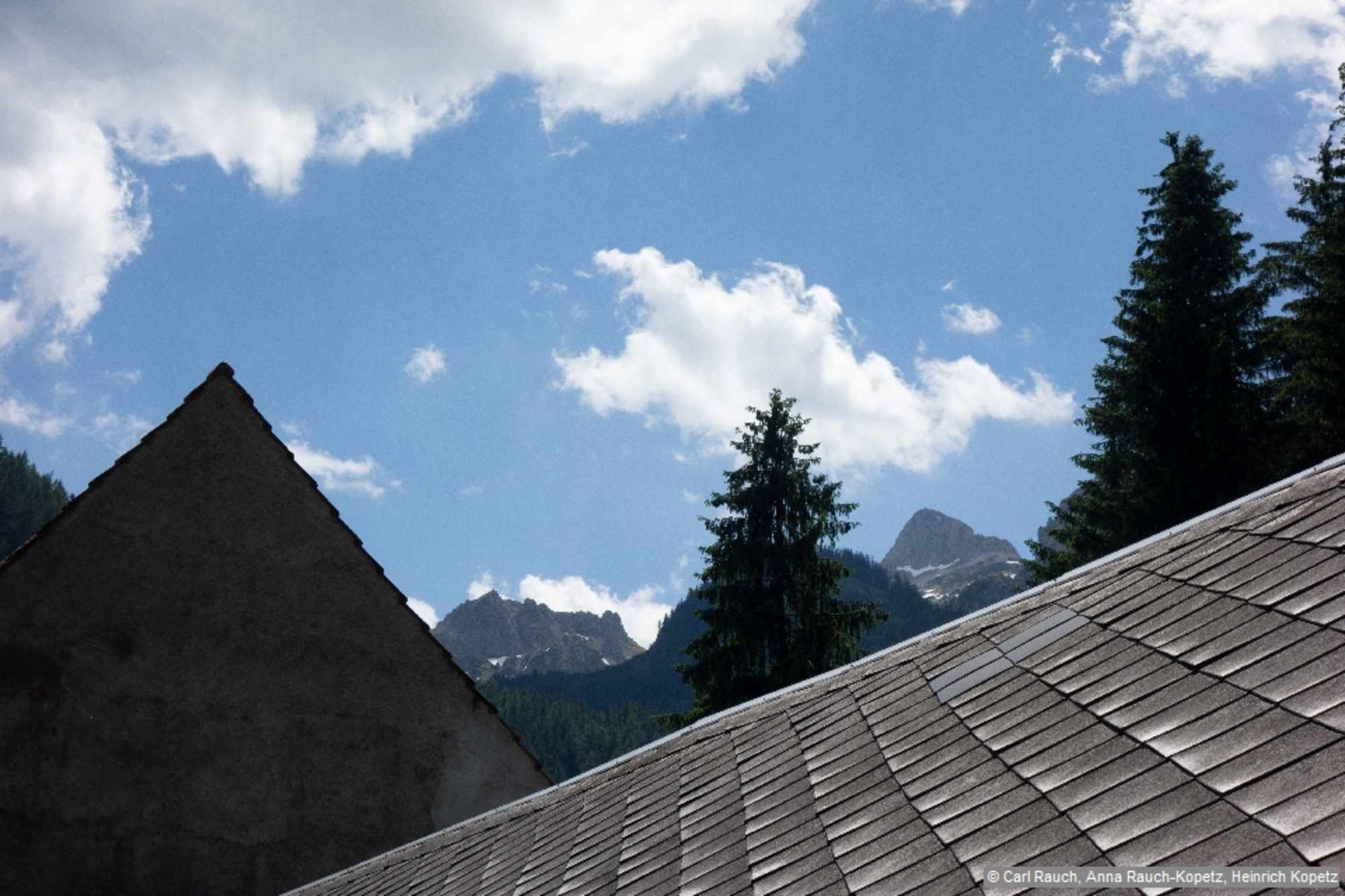 Dachlandschaft im Tal vor der Berglandschaft im Hintergrund.