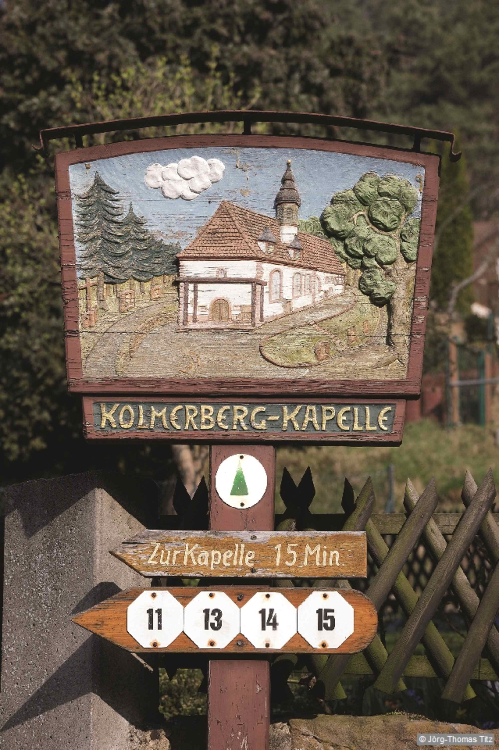 Holzgeschnitztes Schild auf dem Weg zur Kolmerberg-Kapelle.