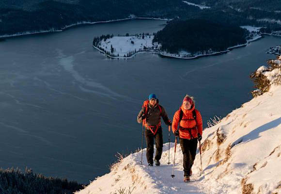 2 Personen gehen auf den Berg wandern im Winter mit Winterkleidung.