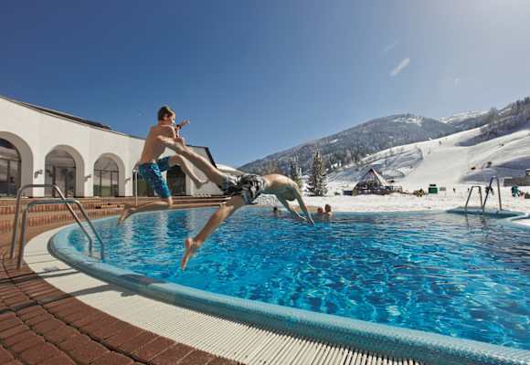 Therme Römerbad mit Außenbecken und direktem Blick auf die Skipiste. 