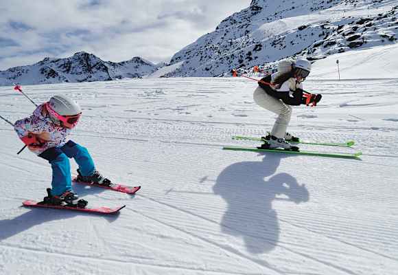 Eine Frau und ein Mädchen fahren gemeinsam Ski und nehmen dabei die Schussposition ein.