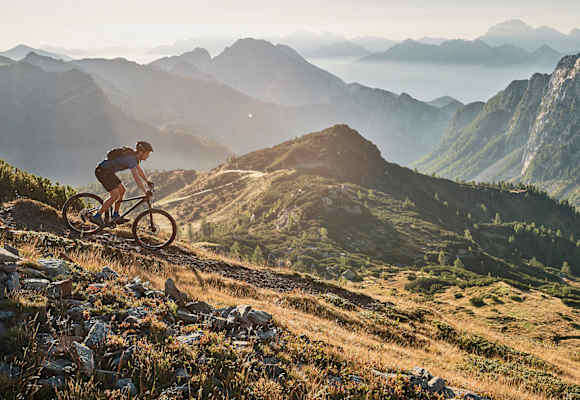 Abwärts in sanftem Licht: Mountainbiken mit Panoramablick.