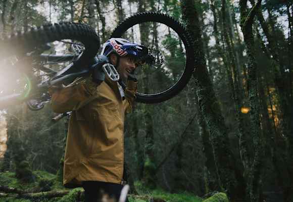 mann hat sein mountainbike auf den schultern, im wald