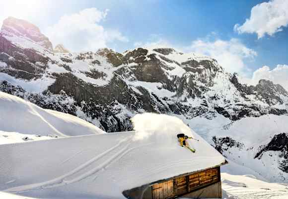 Ein Freerider fährt über das Dach einer Hütte.