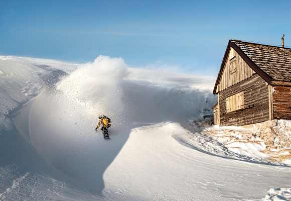 Ein Freerider fährt an einer Hütte vorbei
