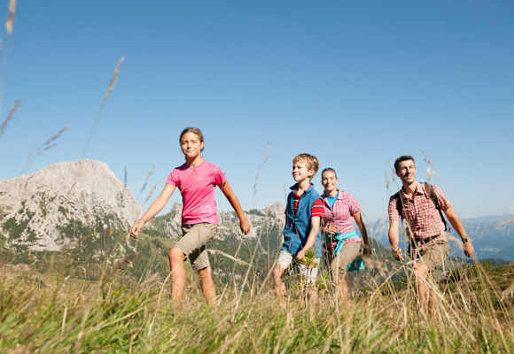 Eine Familie wandert auf einer Alm.